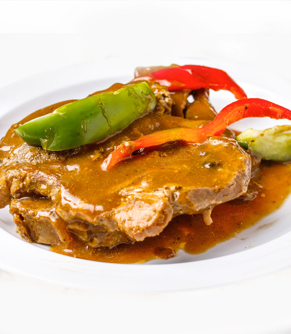 Indulge in our smothered pork chops, featuring juicy chops cooked to perfection and smothered in a rich, savory gravy for a comforting meal.