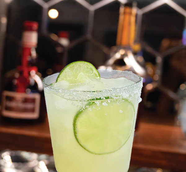 A refreshing classic margarita made with tequila, lime juice, and orange juice, served on the rocks with a salted rim.