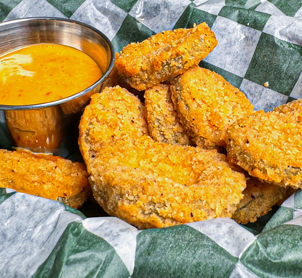 Crispy fried pickles served with a tangy dipping sauce, offering a crunchy and flavorful snack.