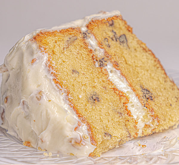 Moist Italian cream cake with layers of cream cheese frosting & pecans, offering a taste of Southern tradition.