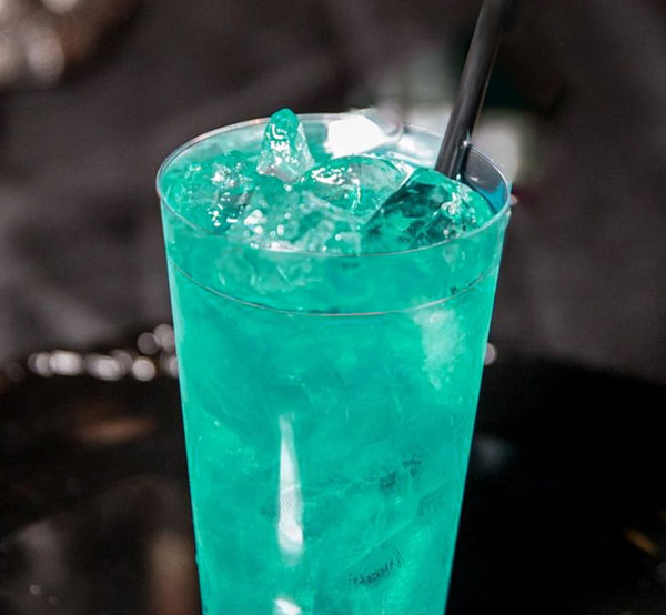 A tropical Mary Jane cocktail made with coconut rum, blue curaçao, spiced rum, pineapple juice, and Sprite, served over ice.