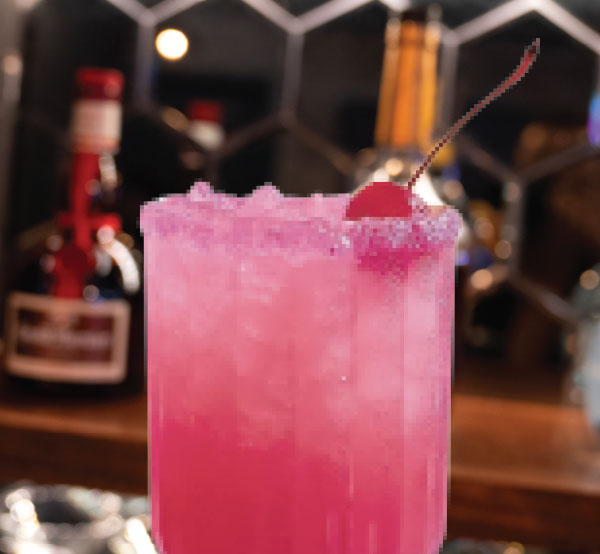 A delightful Pink Lady cocktail made with coconut rum, tropical juices, and grenadine, served over ice for a refreshing treat.