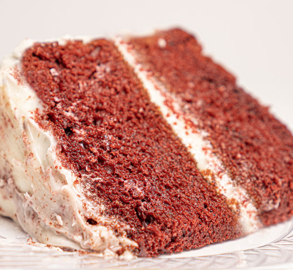 Decadent red velvet cake layered with rich cream cheese frosting, offering a stunning and delicious dessert experience.