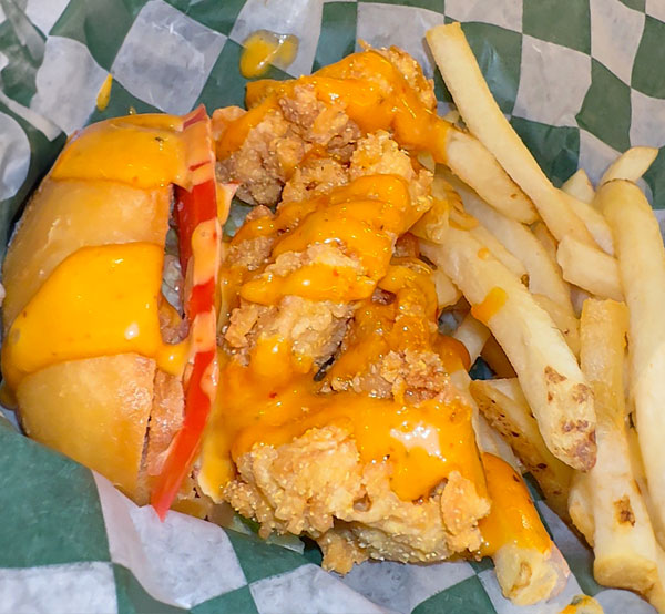 Crispy shrimp po' boy sandwich served with lettuce, tomatoes, and a side of golden fries.